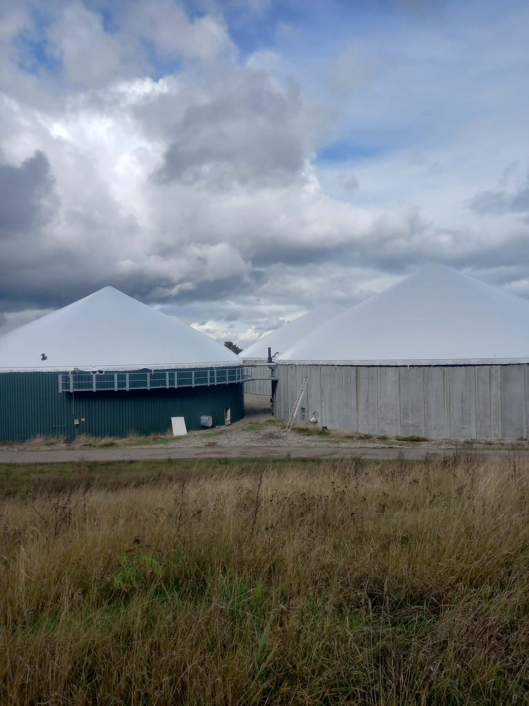 Biogasanlage mit mehreren weißen Membrandächern unter Wolkenhimmel