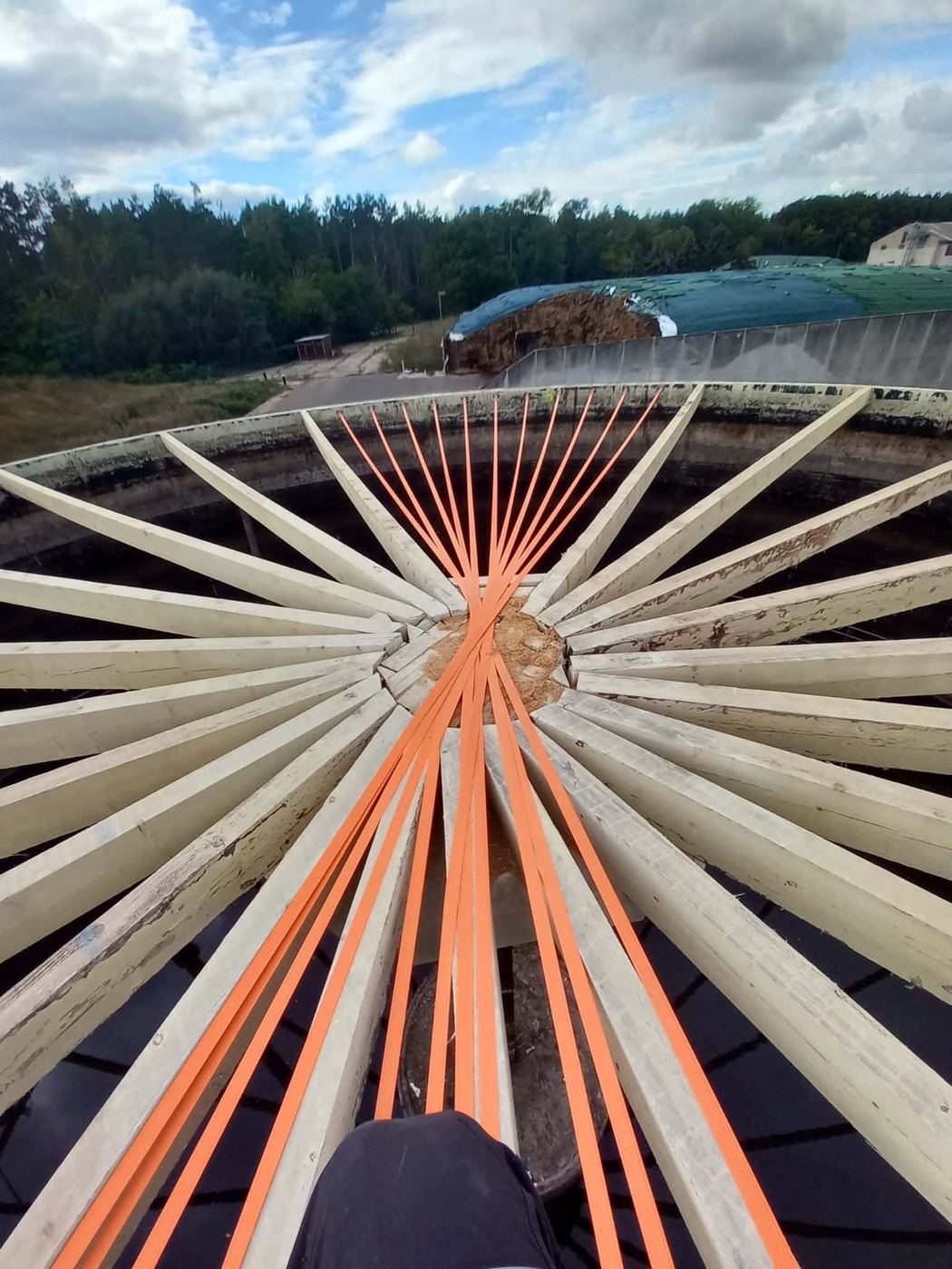 Radiale Dachbalken mit orangen Sicherungsgurten über einem offenen Fermenter